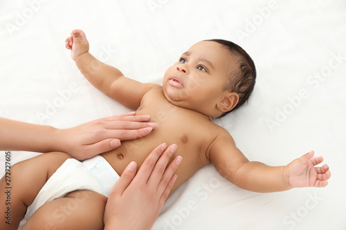 Mother and her cute child on white bed. Baby massage and exercises photo