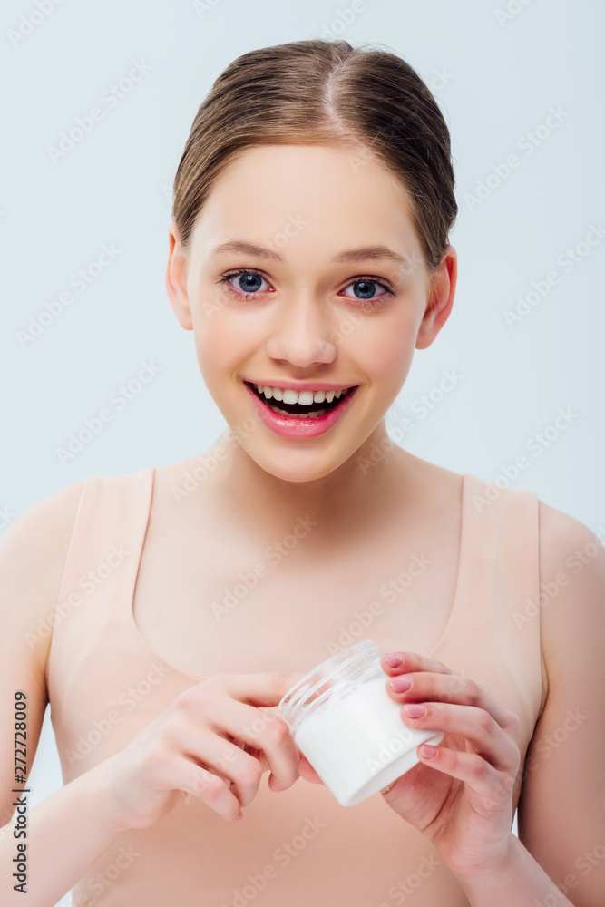 excited teenage girl holding cosmetic cream isolated on grey excited teenage girl holding cosmetic cream isolated on grey