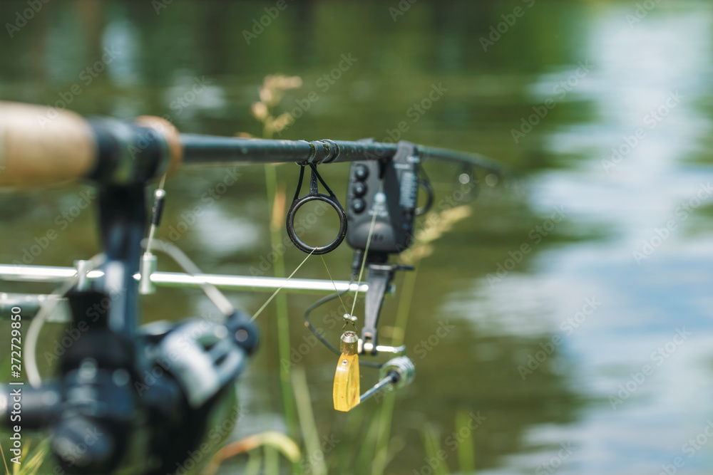 Fishing rod equipped with an electronic bite warning device on the river bank. Fishing rod equipped with an electronic bite warning device on the river bank.