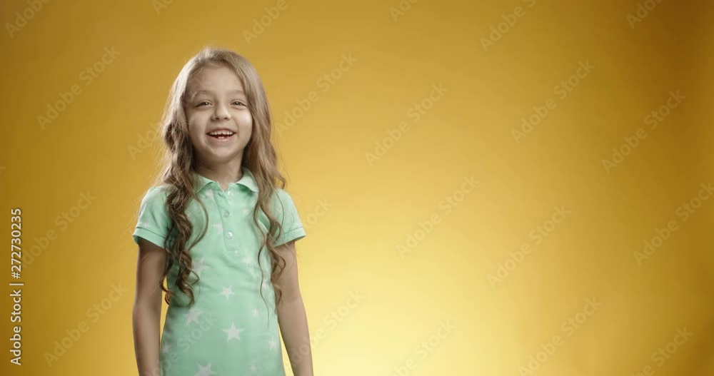 Little caucasian girl pointing in air theen gesturing thumbs up and positively smiling, isolated on yellow background. A template for your graphics close up 4k Little caucasian girl pointing in air theen gesturing thumbs up and positively smiling, isolated on yellow background. A template for your graphics close up 4k