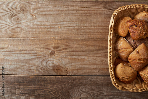 top view of wicker basket with fresh baked buns on wooden table