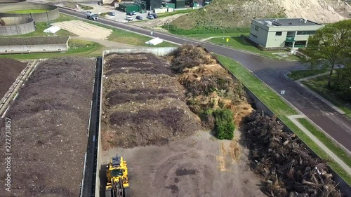 Drone shot of industrial dunghills near some buildings, with some birds flying around, on a sunny day photo