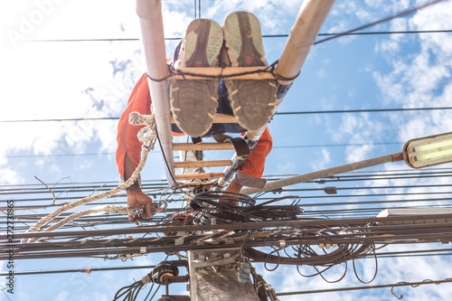 Electrical linemam worker climb a bamboo ladder to repair wire. A telecom engineer installing wire for internet. photo