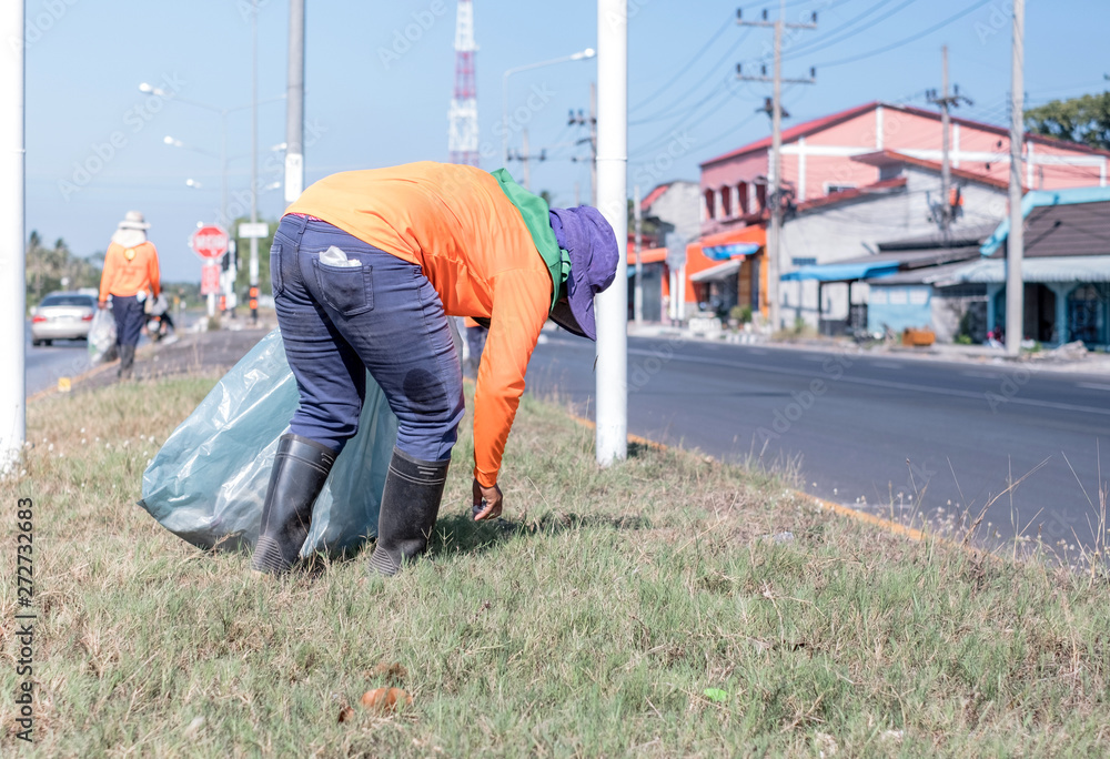 Group of environmental activists picking up trash on hightway road during very hot day.