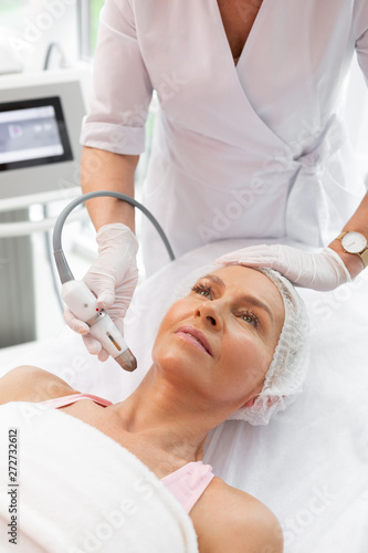 Pleasant aged woman having a special procedure for the neck