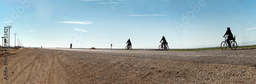 Woman riding a bicycle down a desolate stretch of road in Imperial County California. photo