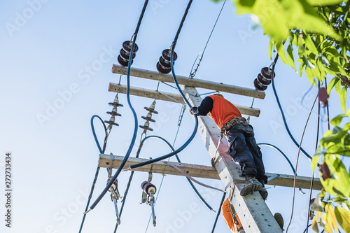 Electrician workers are climbing on the electric poles to install and repair power lines.