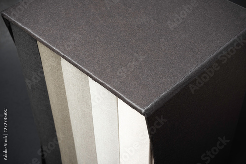 Quadro su tela A set of monochromatic cloth-bound books inside an elegant black hard cardboard slipcase and set on a slightly textured and graduated dark background