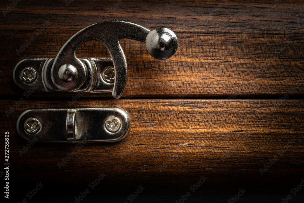 An elegant metal sliding clasp lock screwed into the lid of a wooden box. An elegant metal sliding clasp lock screwed into the lid of a wooden box.