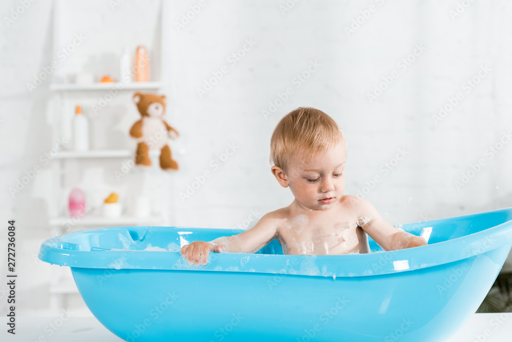 cute toddler kid taking bath and looking at bath foam cute toddler kid taking bath and looking at bath foam