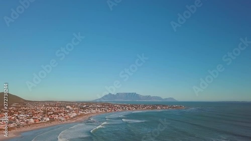 Cinematic wide shot from drone of Table Mountain from Big Bay, Blouberg on a perfect afternoon in Cape Town, South Africa. Jib up to reveal city and Table Mountain. photo