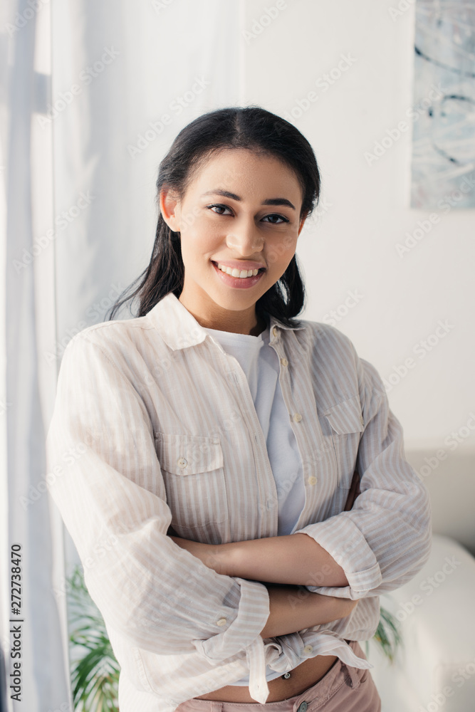 attractive latin woman standing with crossed arms while smiling at camera attractive latin woman standing with crossed arms while smiling at camera