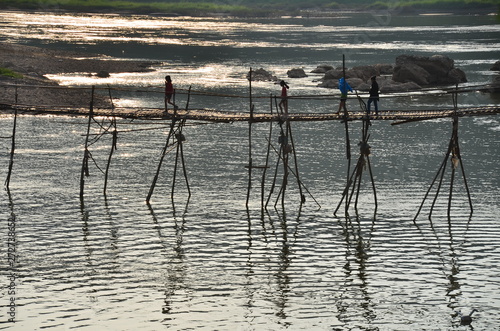ラオスの世界遺産のルアンパバーン　美しい夕日とメコン川　竹の橋を渡る子供