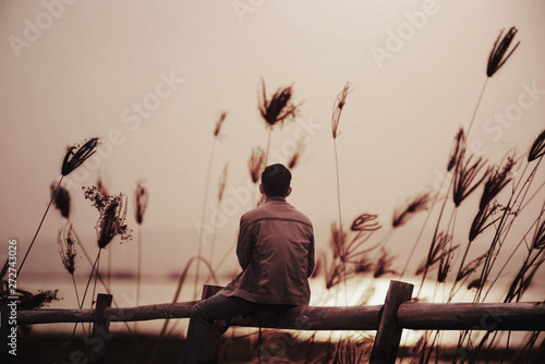 Bilde på lerret A lonely man sitting on the wooden with sunset