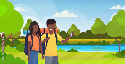 couple tourists hikers using compass searching direction hiking concept man woman african american travelers on hike river landscape background portrait horizontal flat