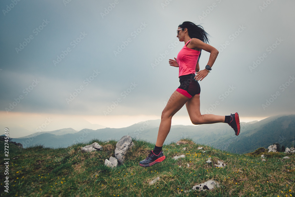 Sporty girl with a beautiful body practicing trail running in the mountains Sporty girl with a beautiful body practicing trail running in the mountains