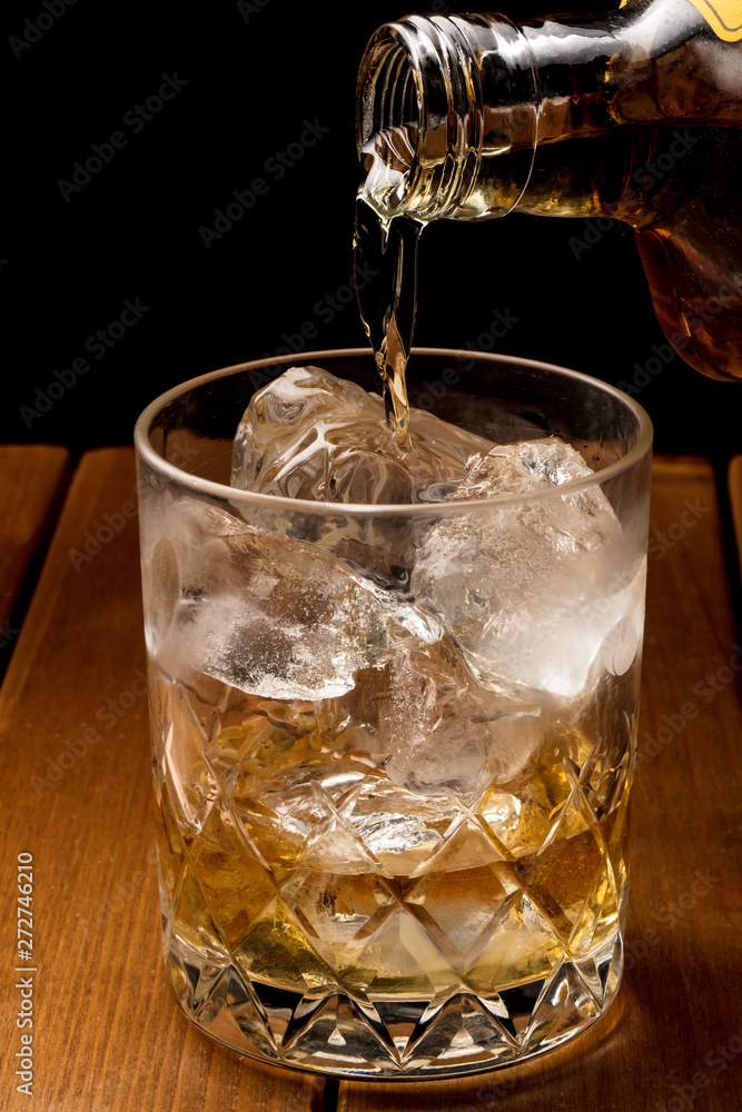 茶色い木目背景でロックグラスにウィスキーを注ぐ Stock 写真 Adobe Stock