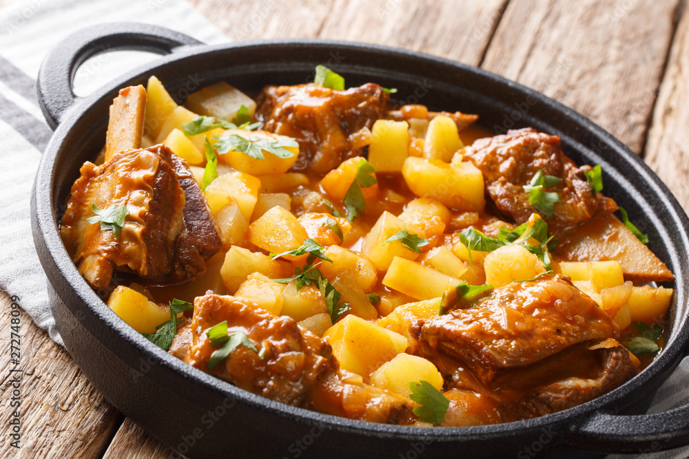 Slow cooked short beef ribs with potatoes in a spicy sauce close-up in a pot. horizontal Slow cooked short beef ribs with potatoes in a spicy sauce close-up in a pot. horizontal