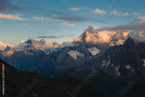 Fototapeta Naklejka Na Ścianę i Meble -  Mountains at sunset. The tops of the mountains are lit by the setting sun. Main Caucasian Range, Dombay, Russia