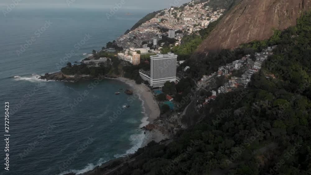 Aerial pan down from the Two Brothers mountain peaks in Rio de Janeiro with the favela of Vidigal to the coastal jungle in the foreground. Tropical coastline and dense urban shantytown community. Aerial pan down from the Two Brothers mountain peaks in Rio de Janeiro with the favela of Vidigal to the coastal jungle in the foreground. Tropical coastline and dense urban shantytown community.