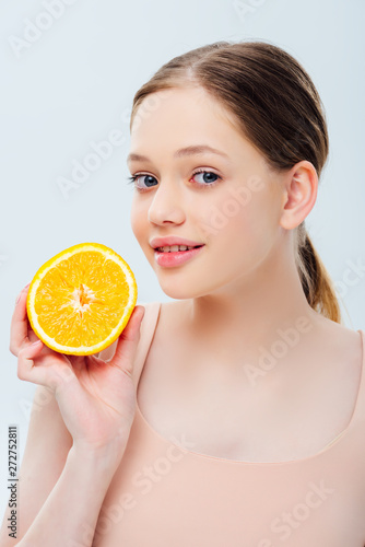 smiling beautiful teenage girl holding ripe orange half isolated on grey