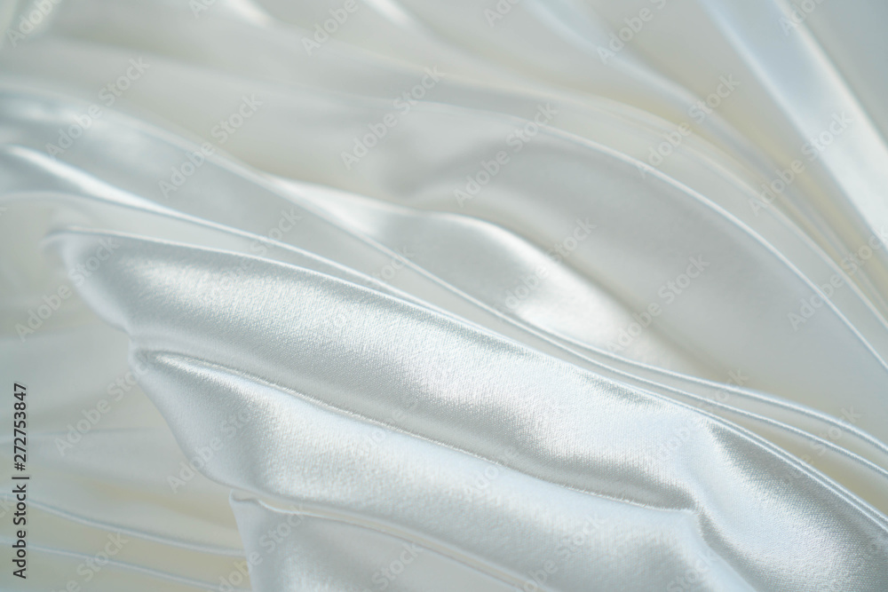 White luxury satin fabric waves background. Rippled white silk fabric satin cloth waves glamour background. Use for cosmetic store or spa salon. Christmas or New Year background design