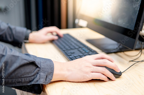 Фотография Male hand holding computer mouse while using desktop computer in furniture store