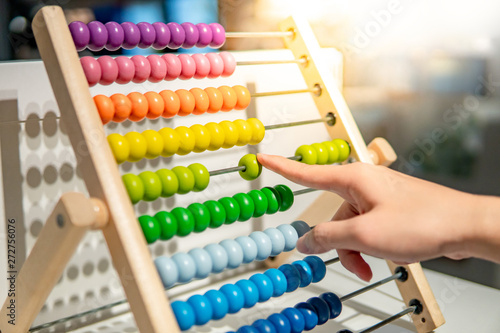 Male hand calculating with beads on wooden rainbow abacus for number calculation. Mathematics learning concept photo