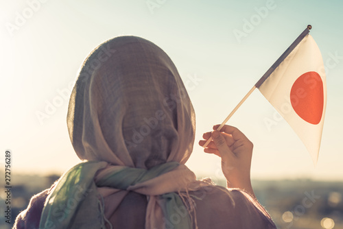 Canvas Print Muslim woman in scarf with Japanese flag of at sunset. Concept