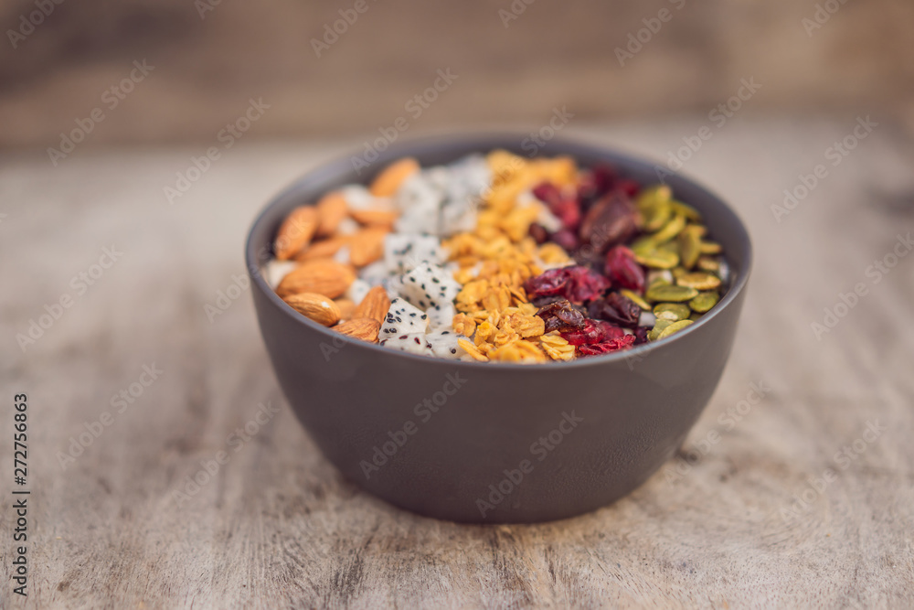 Mango smoothies bowl with almond, dragon fruit, dried cherries, pumpkin seeds and granola on wooden background Mango smoothies bowl with almond, dragon fruit, dried cherries, pumpkin seeds and granola on wooden background