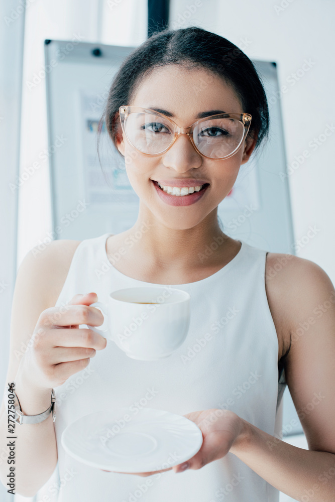 cheerful businesswoman in glasses holding coffee cup and smiling at camera cheerful businesswoman in glasses holding coffee cup and smiling at camera