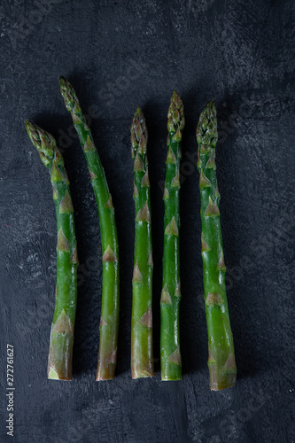 bunches of fresh green asparagus on dark stone background. Top view. vegan food. Ingridients with copy space. Green cocnept. Dieting, healthy food