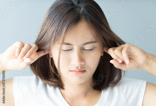 Closeup woman covering ears with her hand, noise problem, selective focus