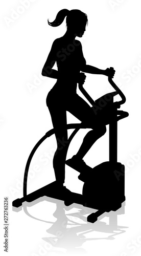 A woman in silhouette using an elliptical cross fit gym equipment exercise machine 