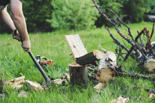 The guy is cutting an old tree in the mountains with an ax. Ukrainian Carpathian Mountains. Bonfire. Tourism. Ax