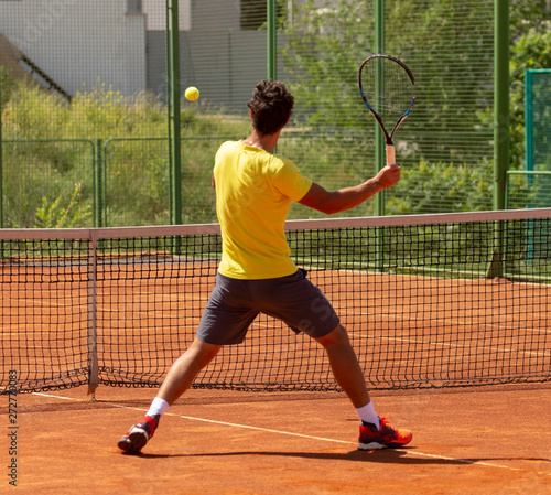 A man plays tennis on the court in the park © schankz