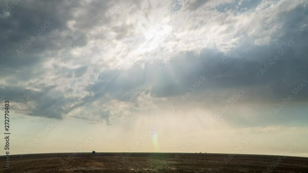 Time lapse of sun rays shining through the clouds moving over flat landscape in the Kansas plains. Time lapse of sun rays shining through the clouds moving over flat landscape in the Kansas plains.