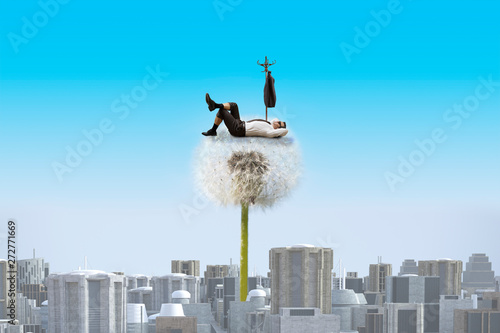 Dandelion towering over a dull city and resting businessman photo