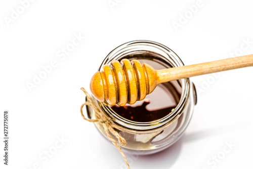 Honey dipper and glass jar of honey isolated on white background
