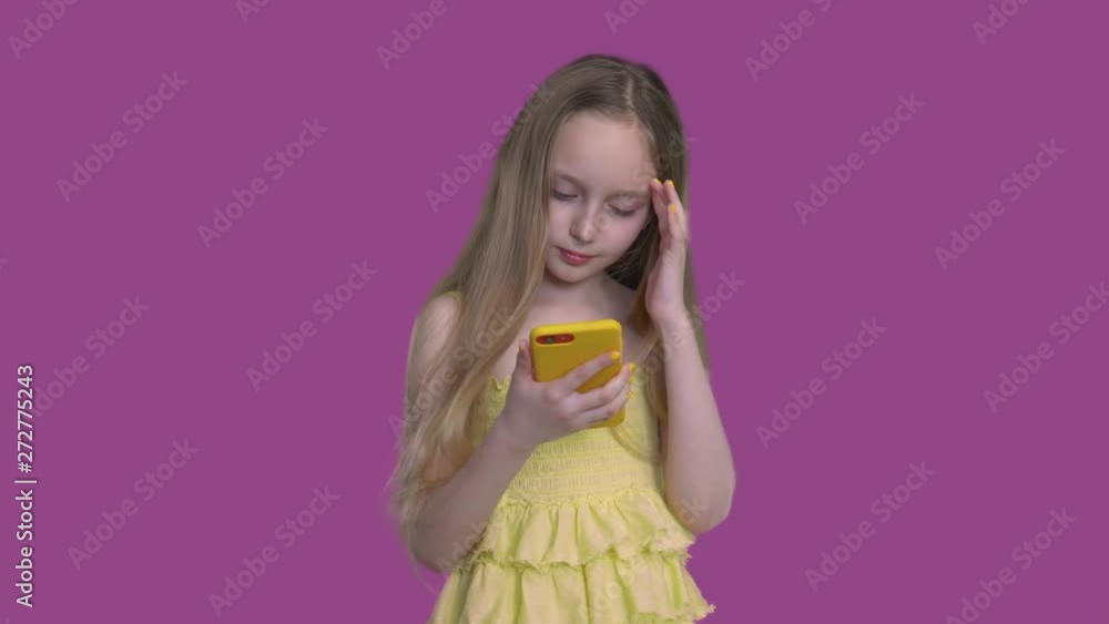 Little Caucasian Girl Looking in Mobile Phone. Glamour Blonde Kid Wearing Pretty Dress Holding Smartphone. Long Hair Blowing. Fashion Child on Neutral Background. Footage Shot Full HD 1080p Little Caucasian Girl Looking in Mobile Phone. Glamour Blonde Kid Wearing Pretty Dress Holding Smartphone. Long Hair Blowing. Fashion Child on Neutral Background. Footage Shot Full HD 1080p