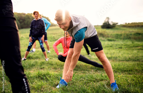Large group of fit and active people doing exercise in nature. © Halfpoint