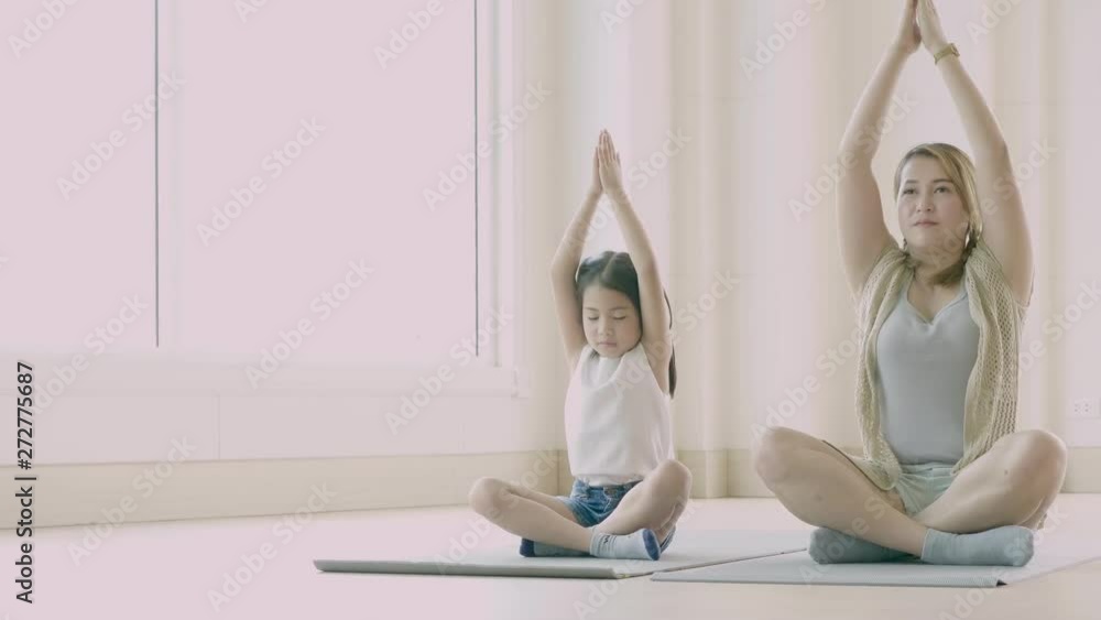 Asian mother and her kid daughter doing stretching exercise at home Asian mother and her kid daughter doing stretching exercise at home