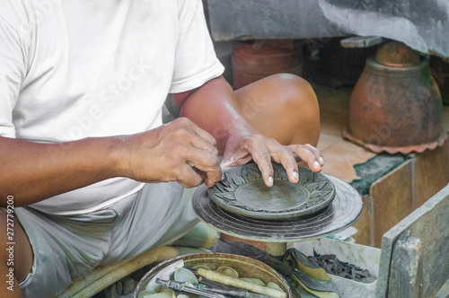 a middle aged man is making a plate with traditional technique using clay