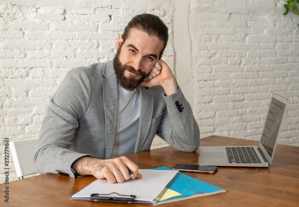 Portrait of happy attractive young businessman working on laptop looking confident Portrait of happy attractive young businessman working on laptop looking confident