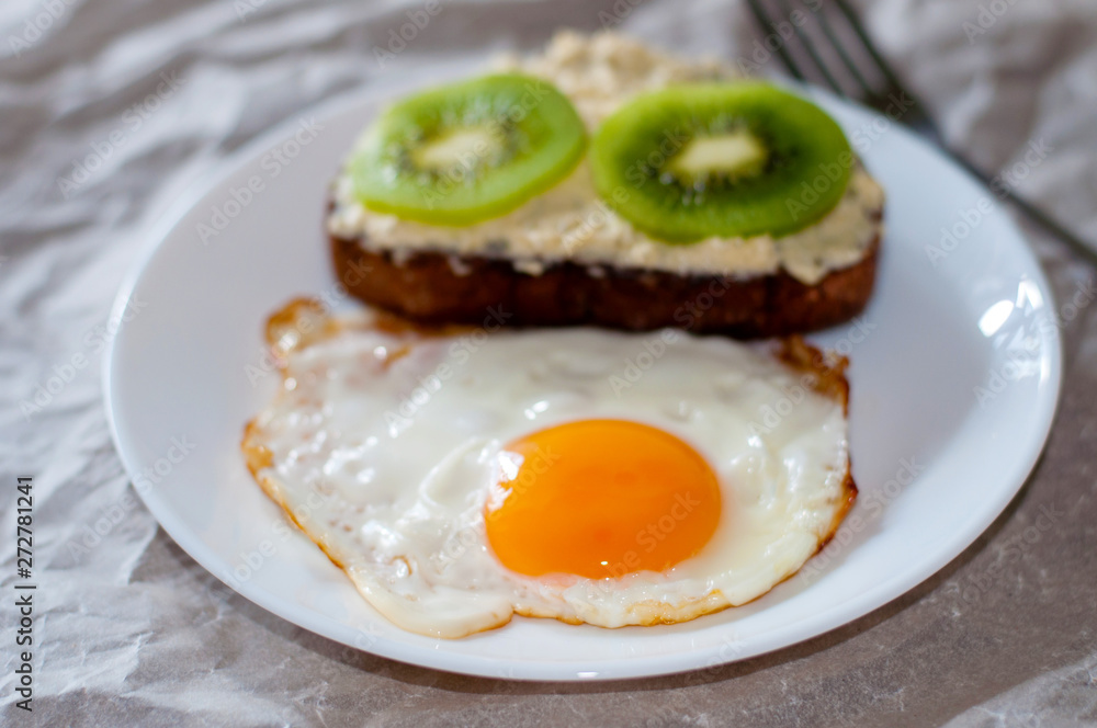 Delicious and healthy breakfast. Fried eggs and kiwi sandwich on white plate Delicious and healthy breakfast. Fried eggs and kiwi sandwich on white plate