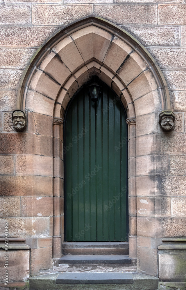 Dark green church entrance door recessed into a sandstone pointed archway