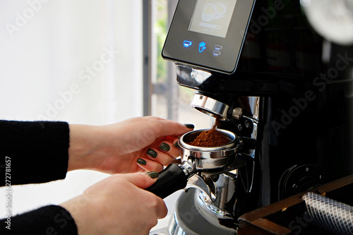 Close up of female barista using modern beautiful coffee machine with vintage style black and chrome texture design to prepare cappuccino. Macro shot of coffee making equipment. Copy space, background