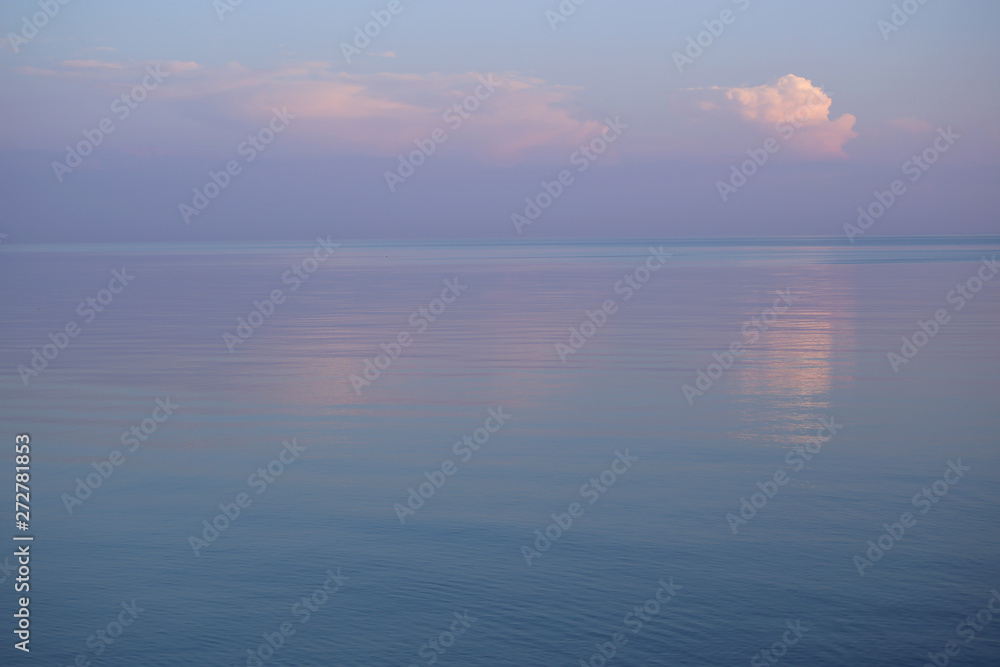 Background of seascape in sunset. Calm sea and purple sky with clouds. 