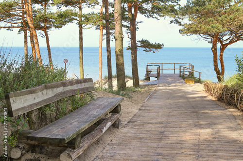 Fototapeta Naklejka Na Ścianę i Meble -  Resting area at sandy beach of the Baltic Sea. Wooden footpath leading to sea with wooden bench and terrace.
