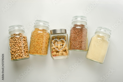Various raw cereals in glass jar. Zero waste concept. Food storage. Flat lay. White background.